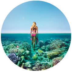 vrouw in bikini loopt in laag water met koraal