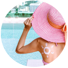 vrouw aan zwembad met zonnehoed en zonnebrand op haar rug